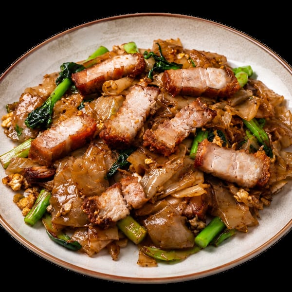 Pad See Ew with crispy pork belly and green vegetables on a white plate.