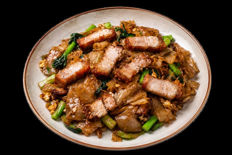 Pad See Ew with crispy pork belly and green vegetables on a white plate.